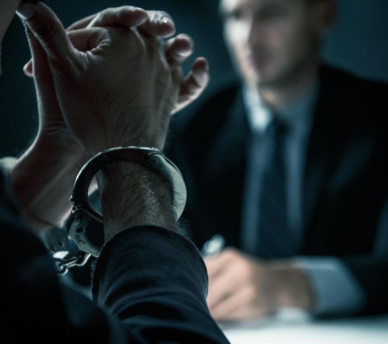Man wearing handcuffs talking to a lawyer