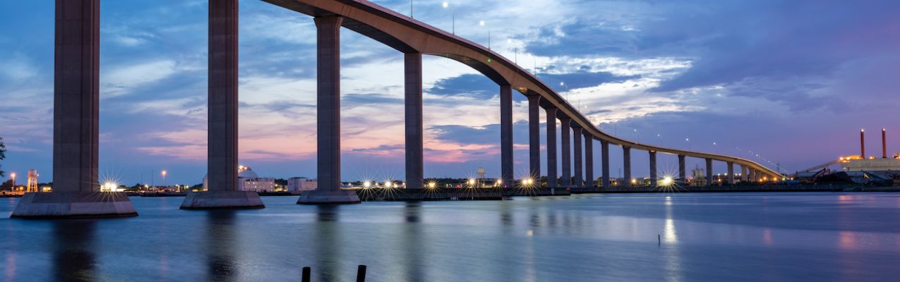 The Jordan Bridge over the Elizabeth River on the border of Norfolk and Chesapeake Virginia against a beautiful red, purple, pink, and blue sunset